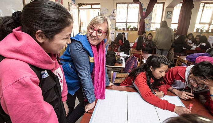 Eine Frau besucht eine Schule in Peru und redet mit einer Einheimischen